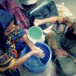 Project staff teaching a mother how to properly wash her hands.