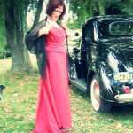 Martina models a vintage red dress in front of their vintage car. One of Marina's many dogs is included here.