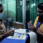 A lab technician assists Piara with her TB testing.